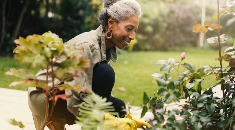 A woman smiling and working in her garden