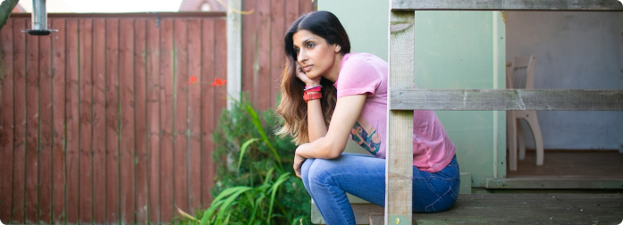 A woman sitting on her backsteps while in deep thought