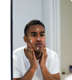 A man looking into a mirror and applying some face lotion